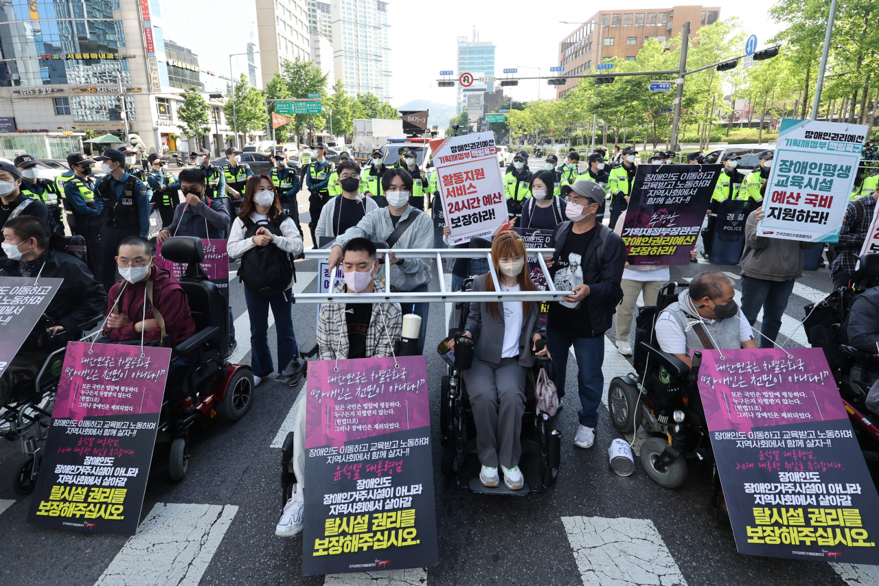 전국장애인차별철폐연대(전장연) 회원들이 지난 16일 오전 서울 용산구 신용산역 인근에서 대통령 집무실로 향하는 한강대로의 횡단보도를 점거한 채 장애인 권리 예산 보장 등을 요구하는 시위를 하고 있다. 같은 날 시위 참가자들은 3~5개 차선의 차량 통행을 막아 출근길 교통 혼잡이 빚어졌다. [연합]