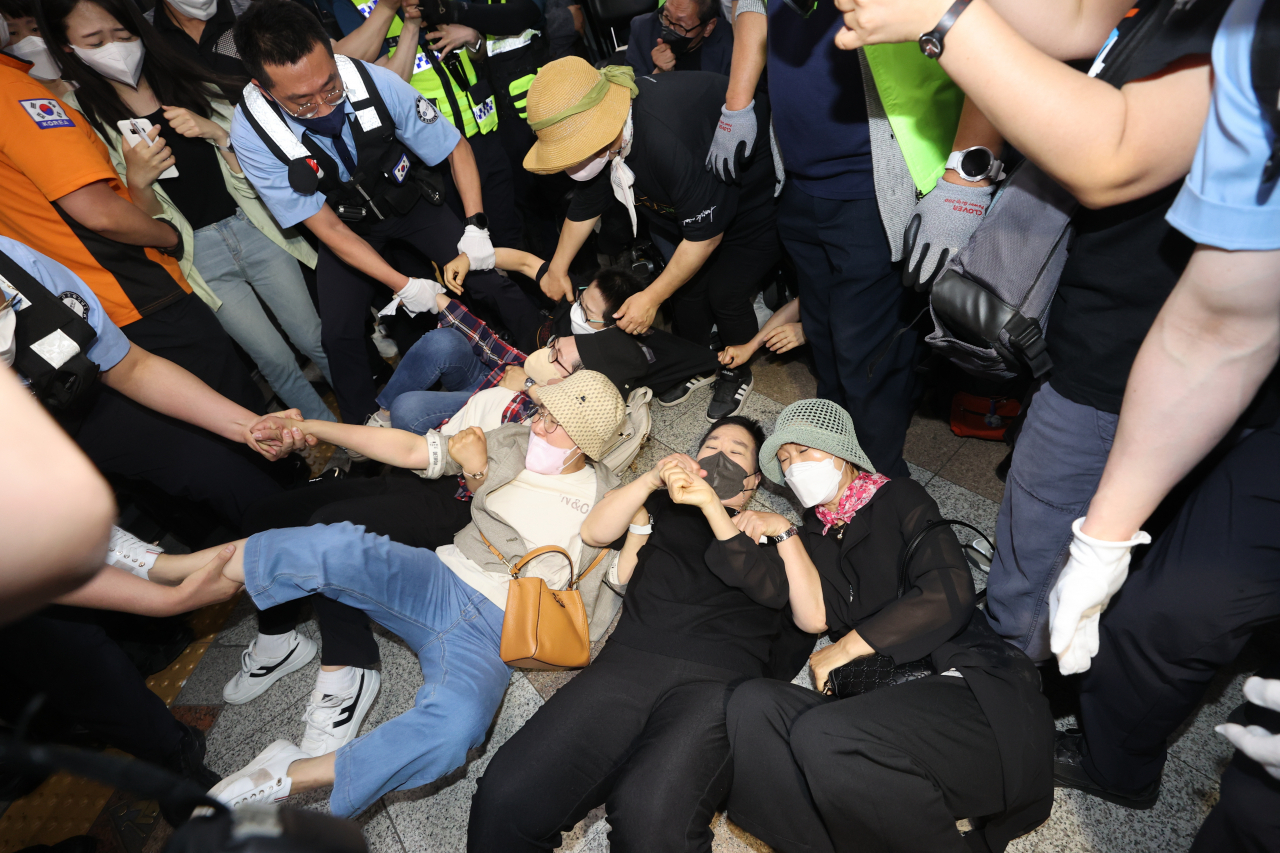 전국장애인부모연대 회원들이 26일 오전 서울 삼각지역 승강장에서 '발달장애인과 그 가족들을 추모하는 분향소'를 설치하는 과정에서바닥에 누워 지하철보안관들과 대치하고 있다. [연합]