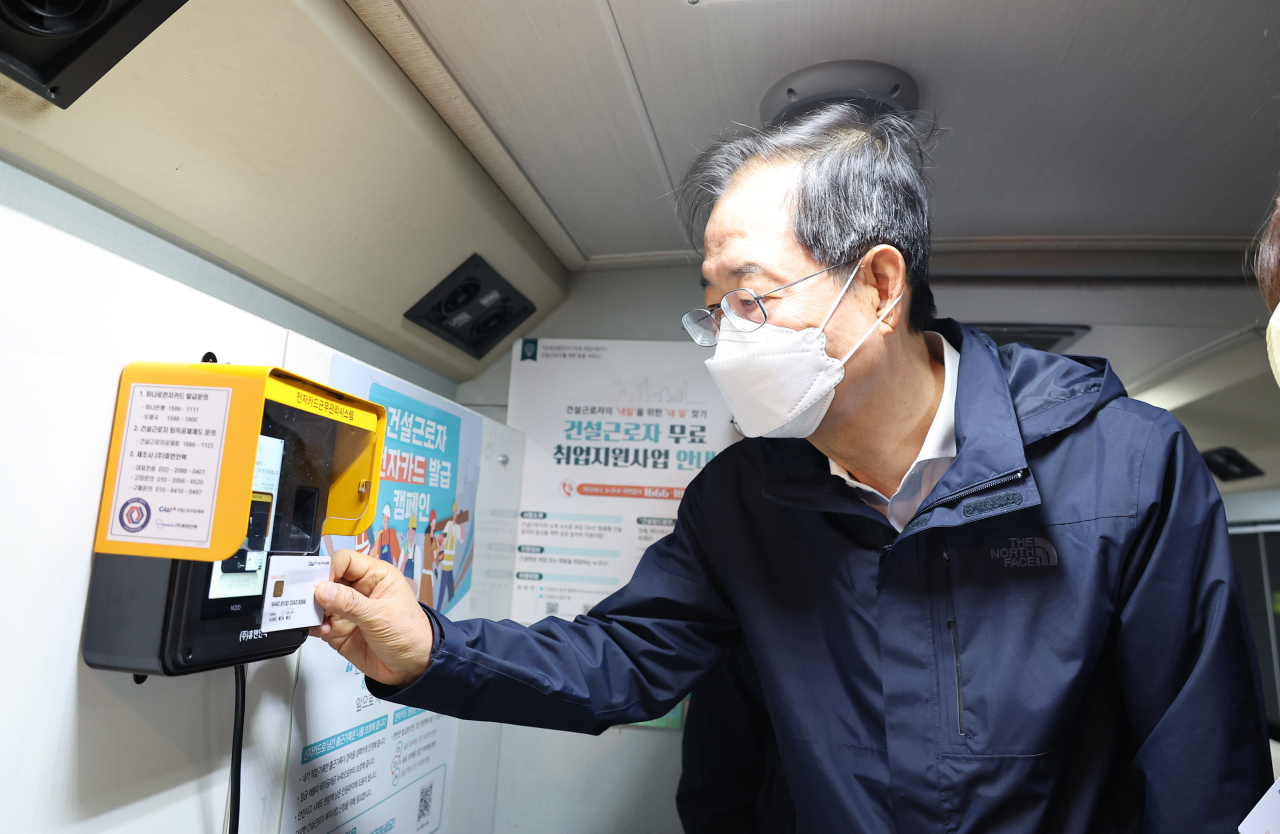 한덕수 국무총리가 27일 새벽 서울 구로구 새벽인력시장을 방문해 종합지원 이동 상담버스를 둘러보며 전자카드근무관리시스템을 시연하고 있다. [연합]