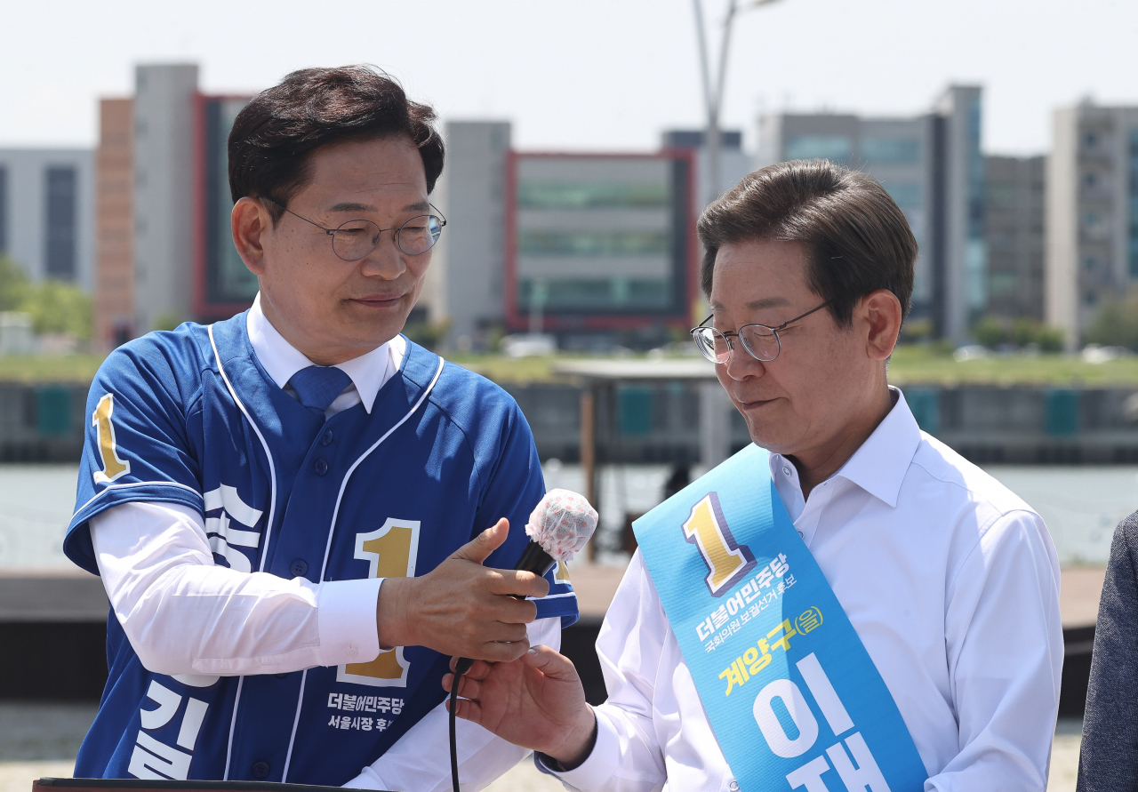 송영길(왼쪽) 더불어민주당 서울시장 후보가 27일 경기도 김포시 고촌읍 아라 김포여객터미널 아라마린센터 앞 수변광장에서 열린 김포공항 이전 수도권 서부 대개발 정책협약식에서 이재명 인천 계양을 국회의원 후보에게 마이크를 건네고 있다. [연합]