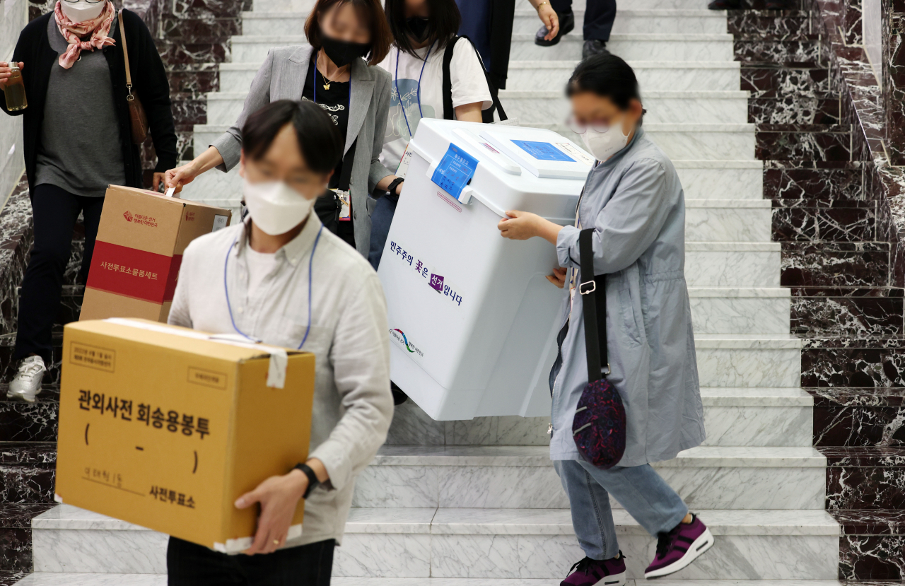 제8회 전국동시지방선거 사전투표 이틀째인 28일 사전투표소에서 관계자들이 관내 투표함과 관외사전 회송용봉투를 옮기고 있다. 연합뉴스
