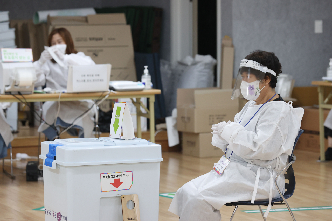 Election officials clad in protective gear await COVID-19 patients and those in quarantine at a polling station in Seoul on Saturday, the final day of two-day early voting for the June 1 local elections. (Yonhap)