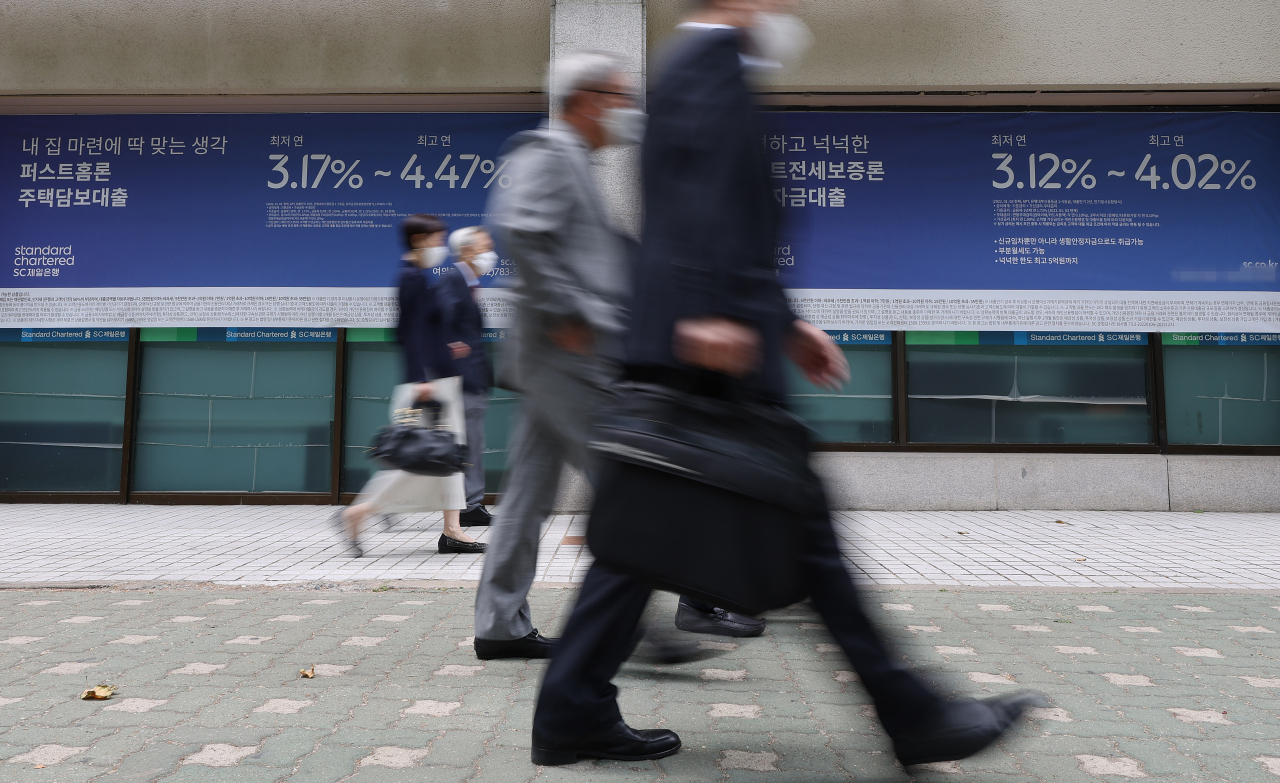 서울의 한 은행에 설치된 대출 관련 안내 현수막 앞으로 시민들이 지나고 있다. [연합]