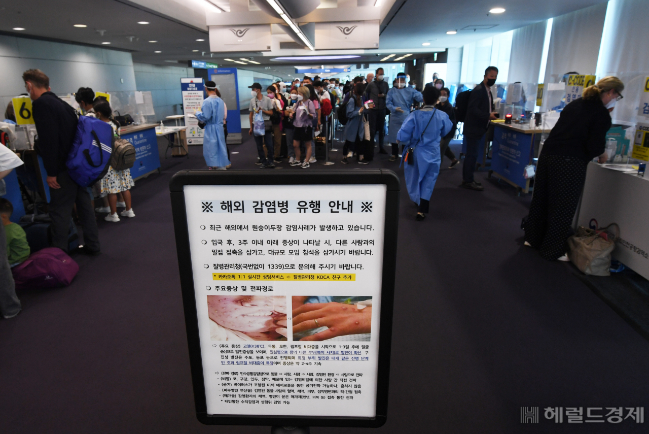 인천국제공항 제1터미널 입국장에 독일 프랑크푸르트와 우즈베키스탄발 탑승객들이 검역을 받기 위해 대기하고 있다. 승객들 앞에는 원숭이두창 관련 안내문이 세워져 있다. [헤럴드경제DB]