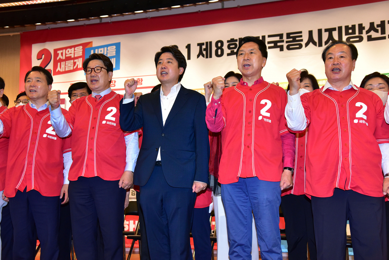 국민의힘 이준석 대표와 지도부가 1일 오후 국회 도서관 대강당에 마련된 지방선거 개표상황실에서 당선이 유력시되는 단체장 후보 사진 밑에 스티커를 붙인 뒤 구호를 외치고 있다. [연합]