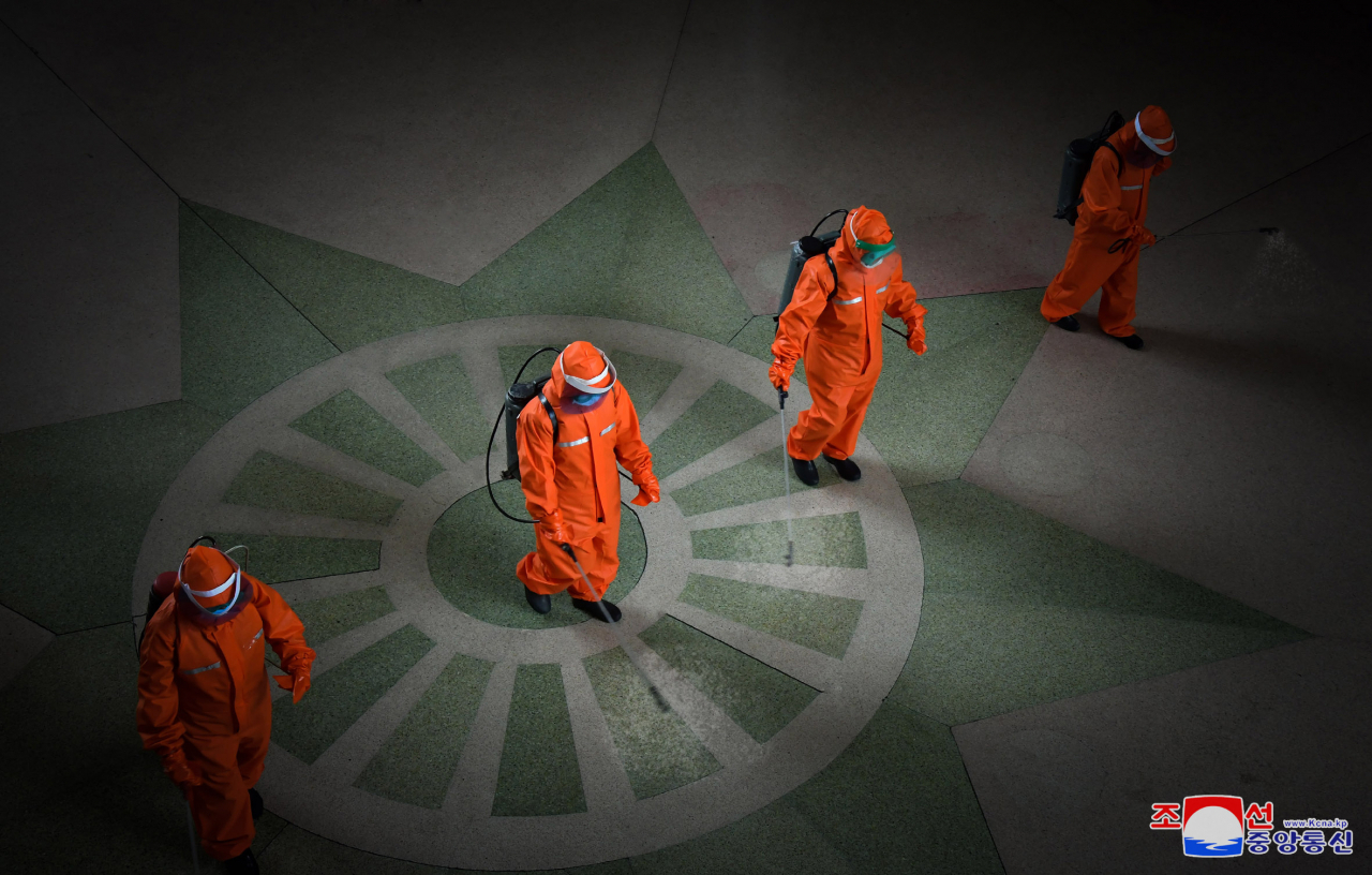 In this file photo released by the North's Korean Central News Agency on May 17, 2022, North Korean health care officials carry out disinfection work at Pyongyang Station in the capital. (KNCA)