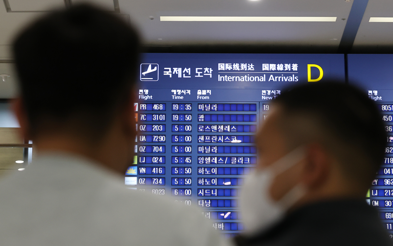 인천국제공항 입국장 전광판에 적혀있는 국제선 도착시간을 보고 있는 승객들 [연합]