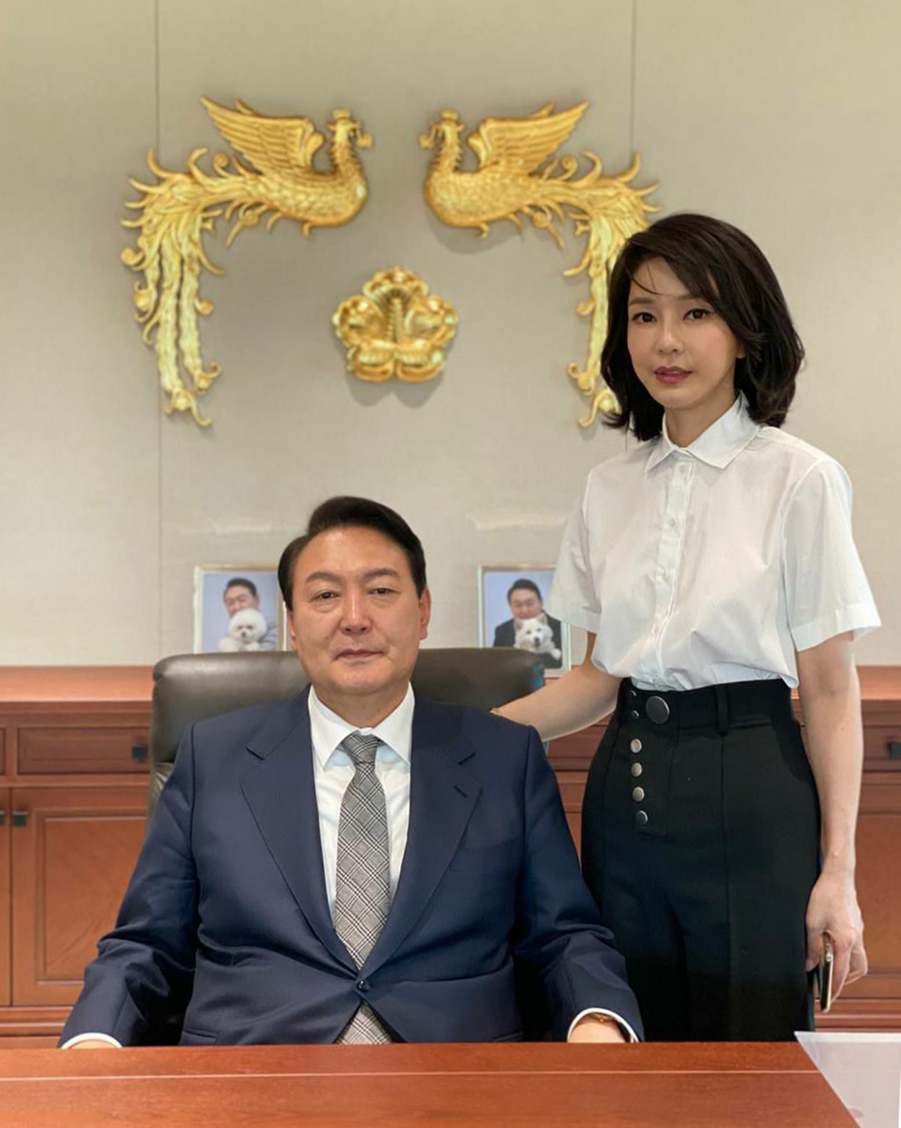 윤석열 대통령과 김건희 여사가 대통령실 집무실에서 대통령 표장을 배경으로 촬영한 사진이 30일 공개됐다. 윤 대통령 뒤로는 반려견 토리, 써니와 함께 찍은 윤 대통령의 사진이 놓여 있다. [연합]