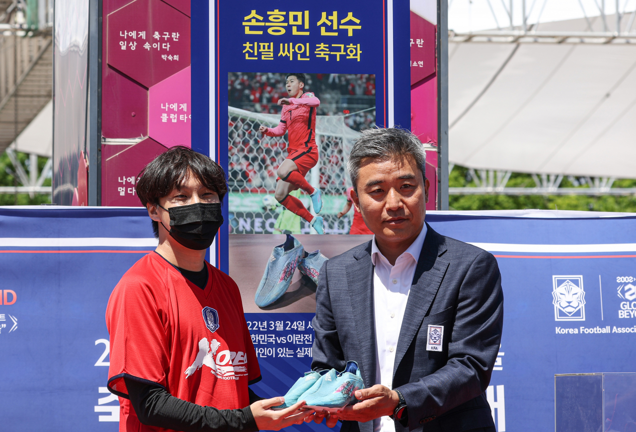 6일 오후 서울 마포구 서울월드컵경기장 북측 광장에서 2002년 월드컵 20주년 기념 대국민 프로젝트 '2022 KFA 풋볼 페스티벌' 도중 열린 축구 스타 소장품 경매 행사에서 축구 국가대표팀 주장 손흥민이 지난 3월 24일 월드컵 예선 이란전에서 결승 골을 넣을 때 신었던 축구화를 1600 만원에 낙찰받은 축구팬 이재호씨가 축구협회 관계자에게 전달받고 있다. 이날 경매에서 낙찰된 물건들의 대금은 모두 기부될 예정이다. [연합뉴스]