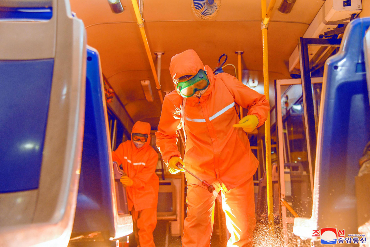 This photo, released by North Korea's official Korean Central News Agency last Saturday, shows workers sterilizing the inside of a train in Pyongyang. North Korea reported about 79,100 new suspected COVID-19 cases on the day. (KCNA)