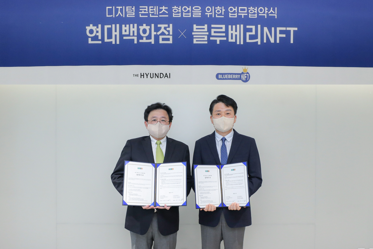 9일 서울 강남구에 위치한 현대백화점 사옥에서 권태진 현대백화점 디지털사업본부장(오른쪽)과 홍상혁 블루베리NFT 대표이사가 MOU체결 후 기념촬영을 하고 있는 모습.[현대백화점 제공]