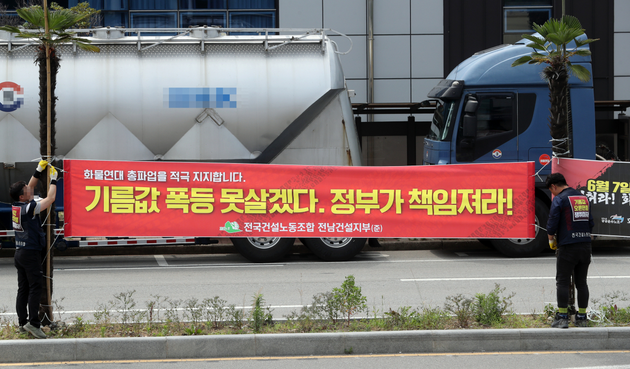 민주노총 공공운수노조 화물연대본부(이하 화물연대) 총파업 사흘째인 9일 전남 여수시 여수국가산업단지의 도로에서 건설노조 조합원들이 파업을 지지하는 내용의 현수막을 내걸고 있다. 연합뉴스