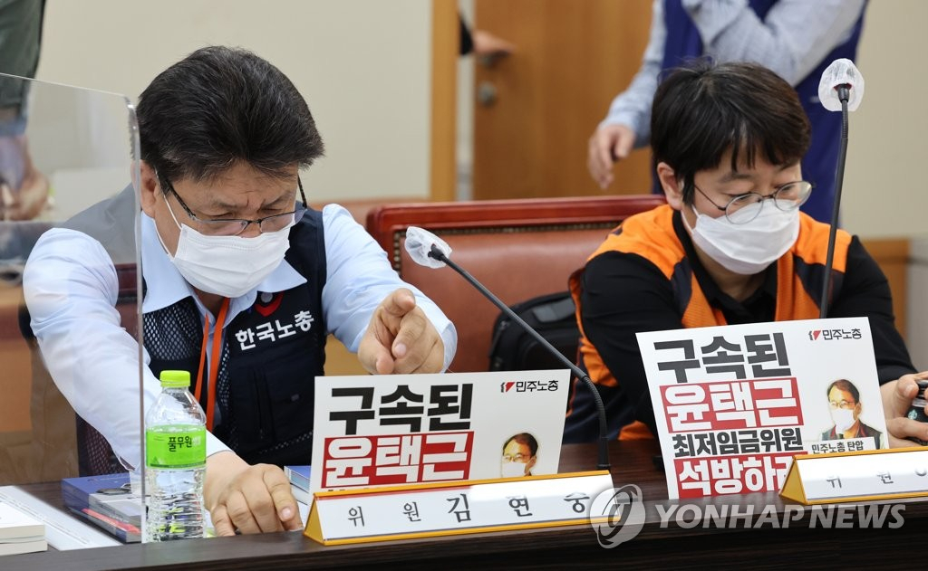 지난 5월 17일 오후 세종시 정부세종청사 최저임금위원회 회의실에서 열린 제2차 전원회의에 참석한 근로자 위원들이 '구속된 윤택근 최저임금위원 석방하라' 라고 적힌 손팻말을 테이블에 올리고 있다. [연합]