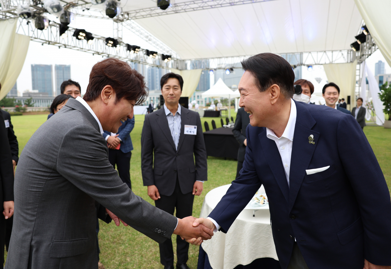 윤석열 대통령이 12일 오후 서울 용산 대통령실 청사 잔디마당에서 열린 영화관계자 초청 만찬에서 한국 배우 최초로 칸국제영화제에서 남우주연상을 수상한 배우 송강호와 인사하고 있다. [연합]