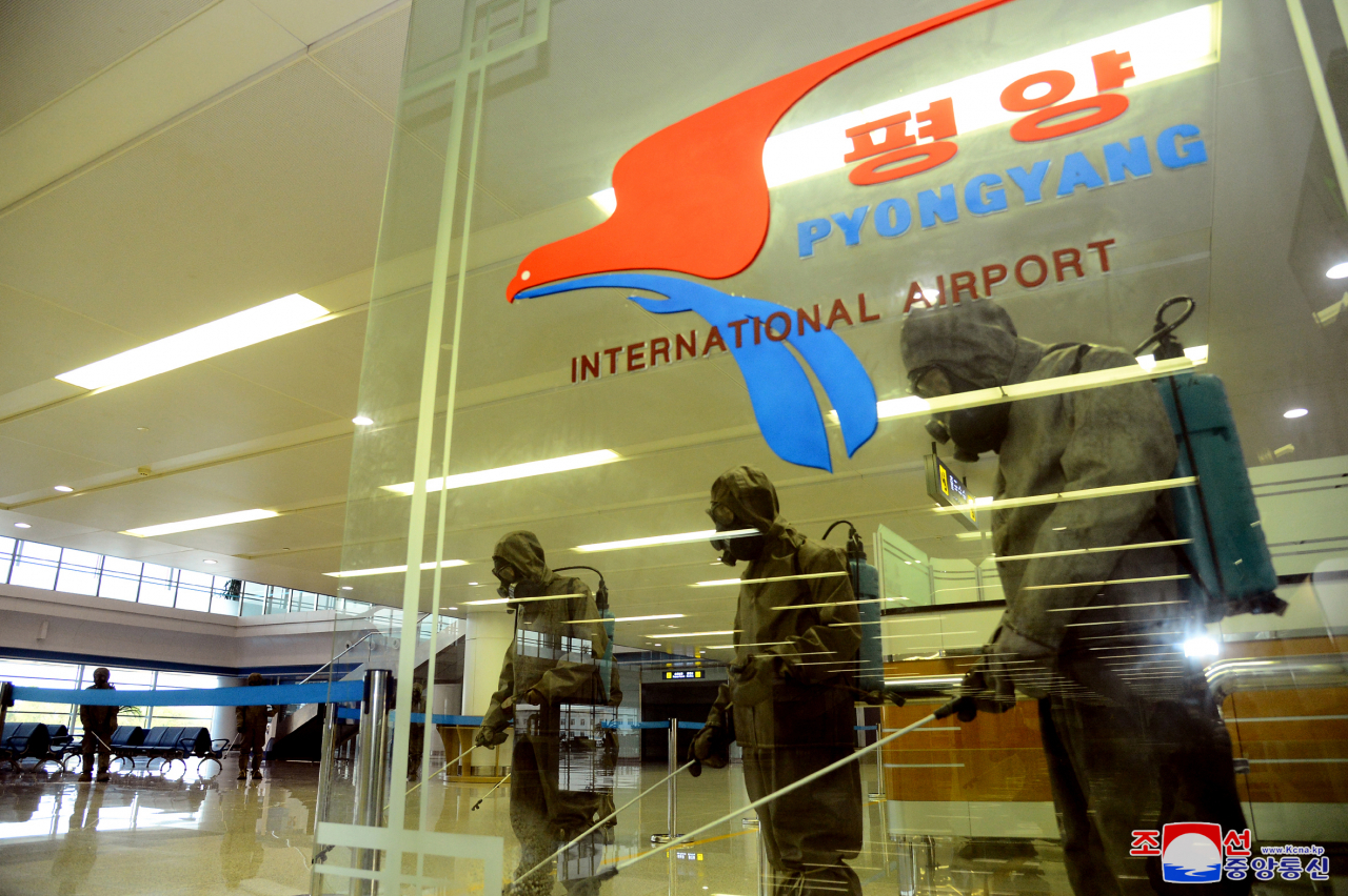 Quarantine officials spray disinfectant at Pyongyang International Airport in the North Korean capital amid the highest-level alert on the coronavirus, in this undated photo released by the North's Korean Central News Agency last Friday. (Yonhap)