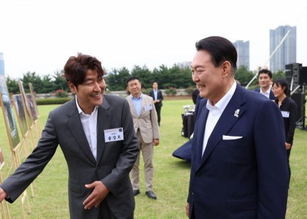윤석열 대통령이 12일 오후 서울 용산 대통령실 청사 잔디마당에서 열린 영화관계자 초청 만찬에서 한국 배우 최초로 칸국제영화제에서 남우주연상을 수상한 배우 송강호와 사진을 보며 대화하고 있다. [연합]