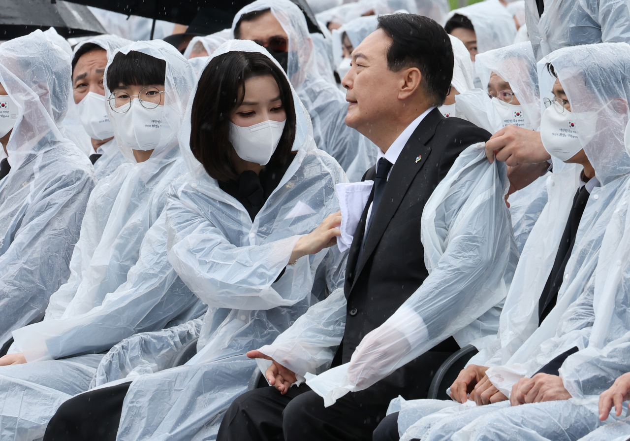 6일 오전 서울 동작구 국립서울현충원에서 열린 제67회 현충일 추념식에서 김건희 여사가 비에 젖은 윤석열 대통령의 옷을 닦아주고 있다. [연합]