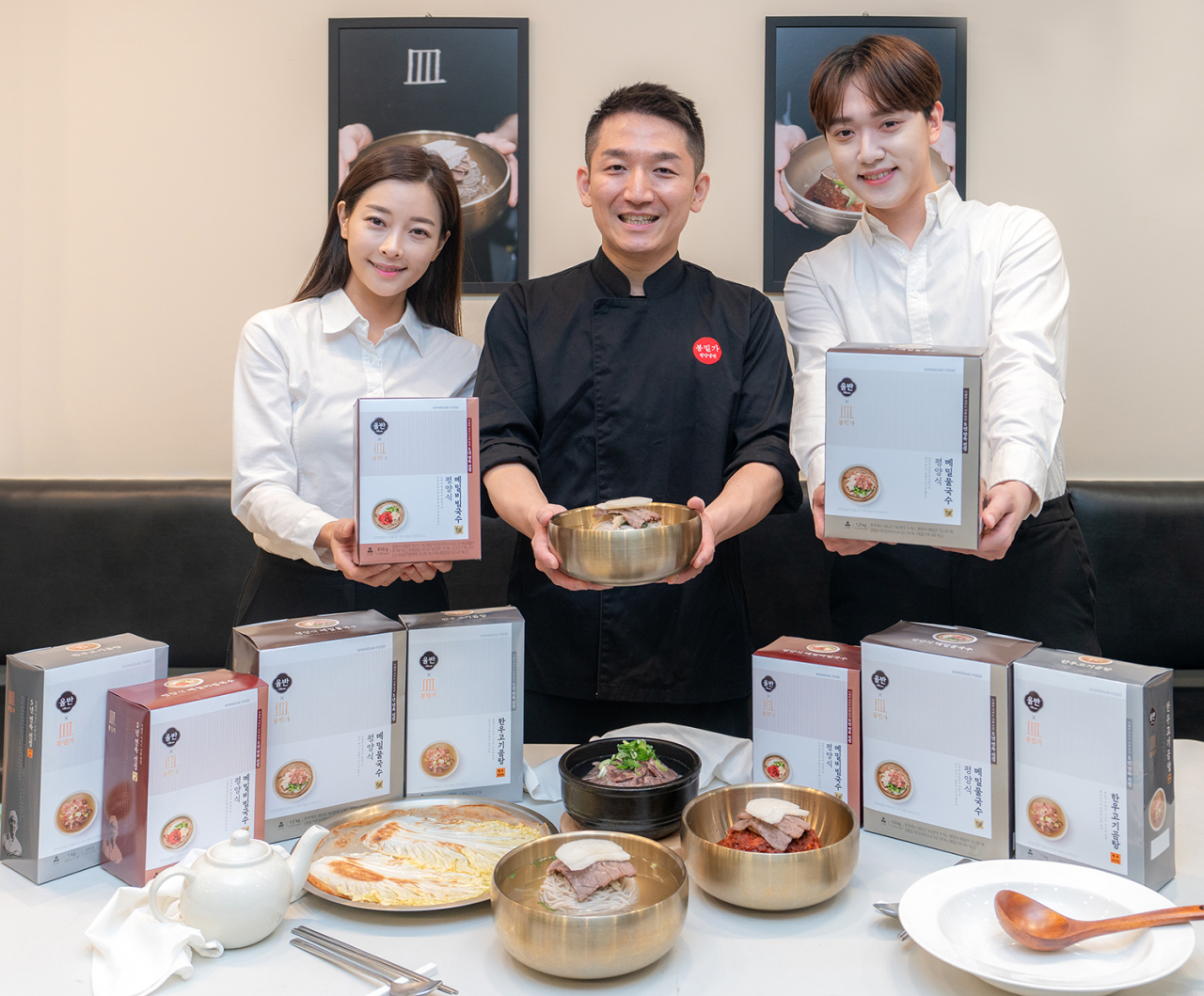 권희승 봉밀가 대표(가운데)와 모델들이 신세계푸드가 미쉐린 가이드 서울에 5년 연속 선정된 냉면 맛집 봉밀가와 협업을 통해 출시한 평양식 메밀국수와 한우고기곰탕 등 간편식을 소개하고 있다. [신세계푸드 제공]