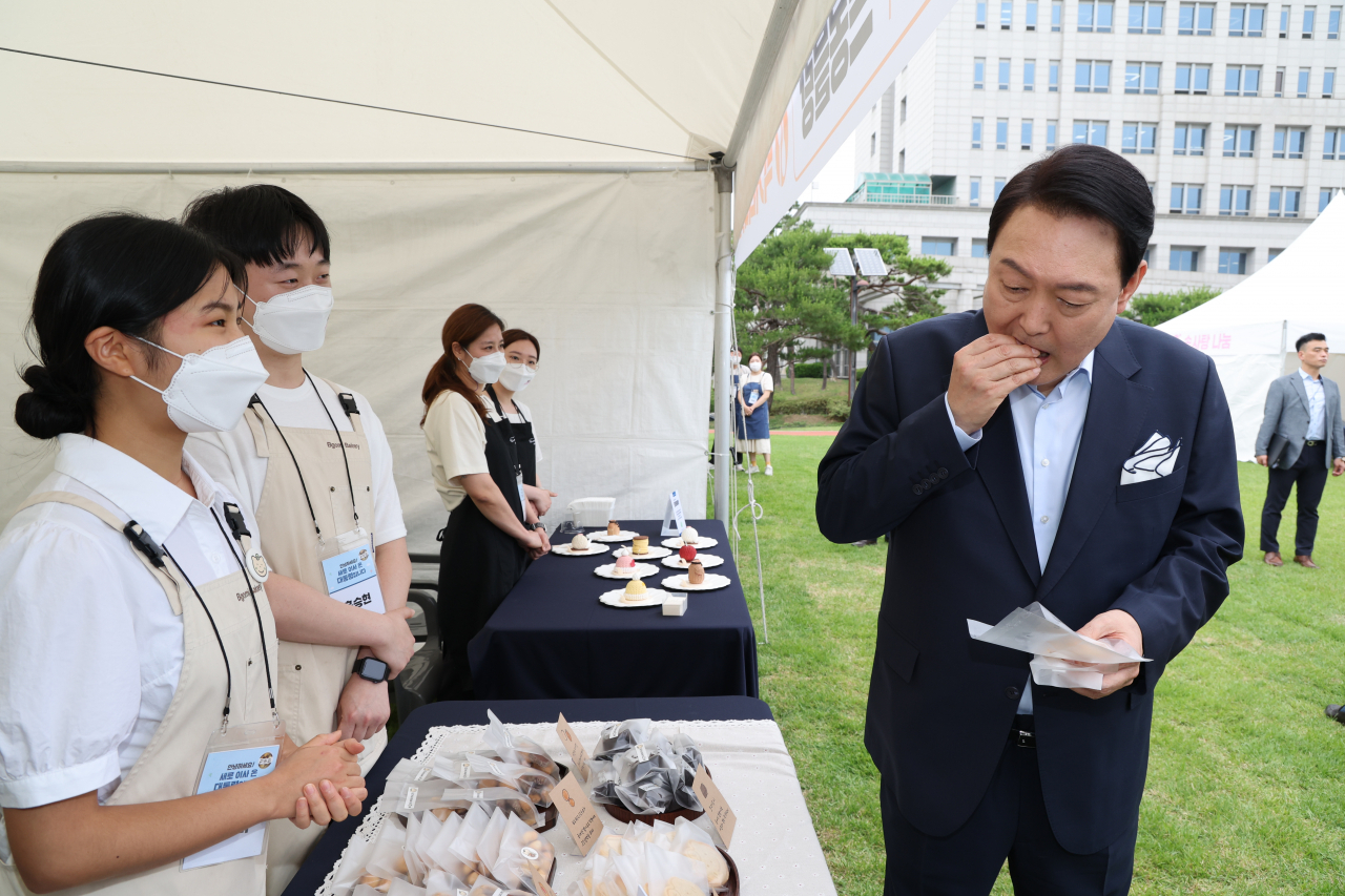 윤석열 대통령이 19일 오후 용산 대통령실 청사 앞 잔디광장에서 열린 대통령실 이전 기념 주민 초대 행사에서 용산 지역 소상공인이 참여한 먹거리 장터를 둘러보다 쿠키를 맛보고 있다. [연합]