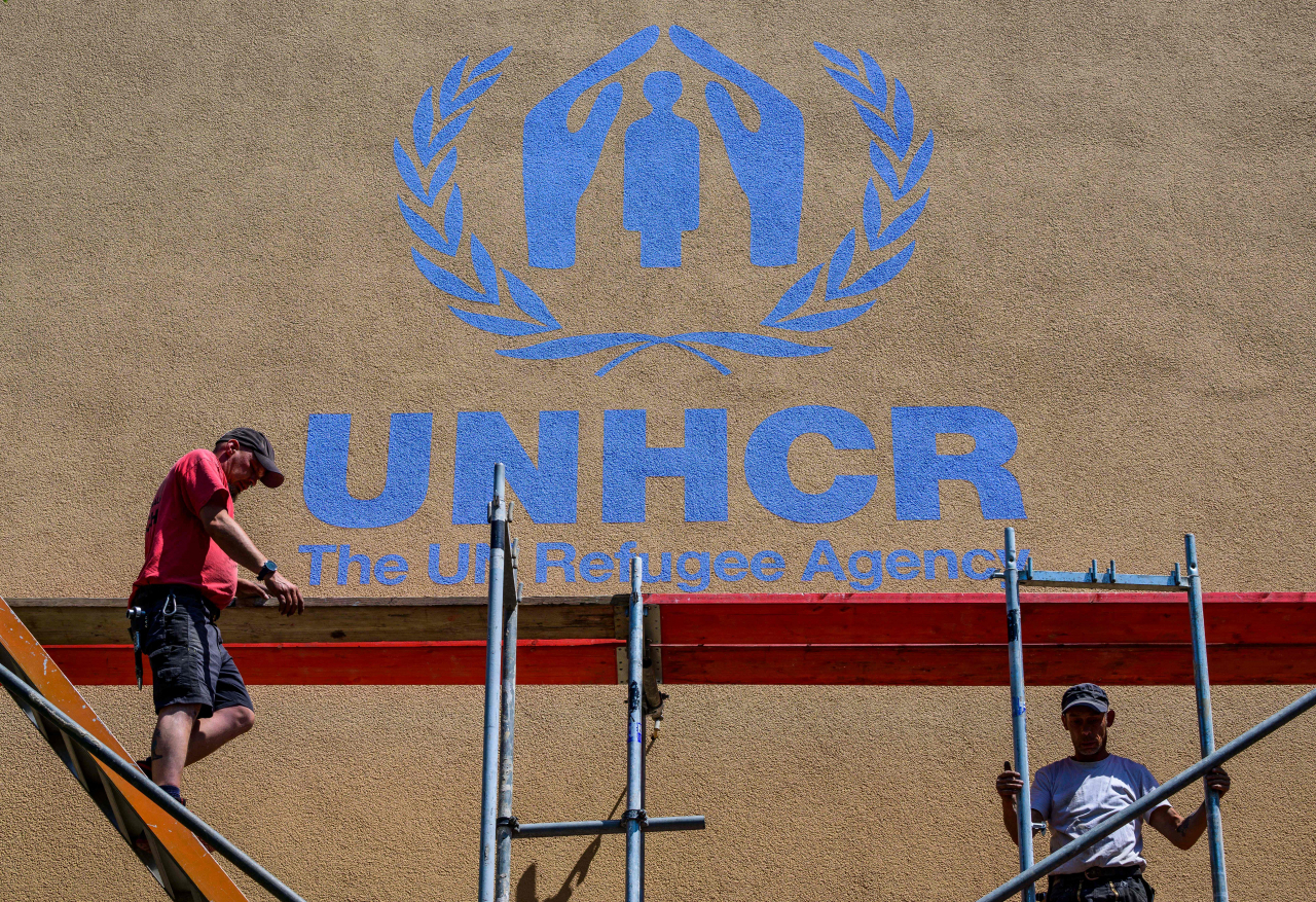 독일 베를린 북부에 있는 난민을 위한 거주시설에서 작업자들이 외벽에 유엔난민기구(UNHCR)이란 로고를 그려넣은 뒤 비계를 해체하고 있다. [AFP]