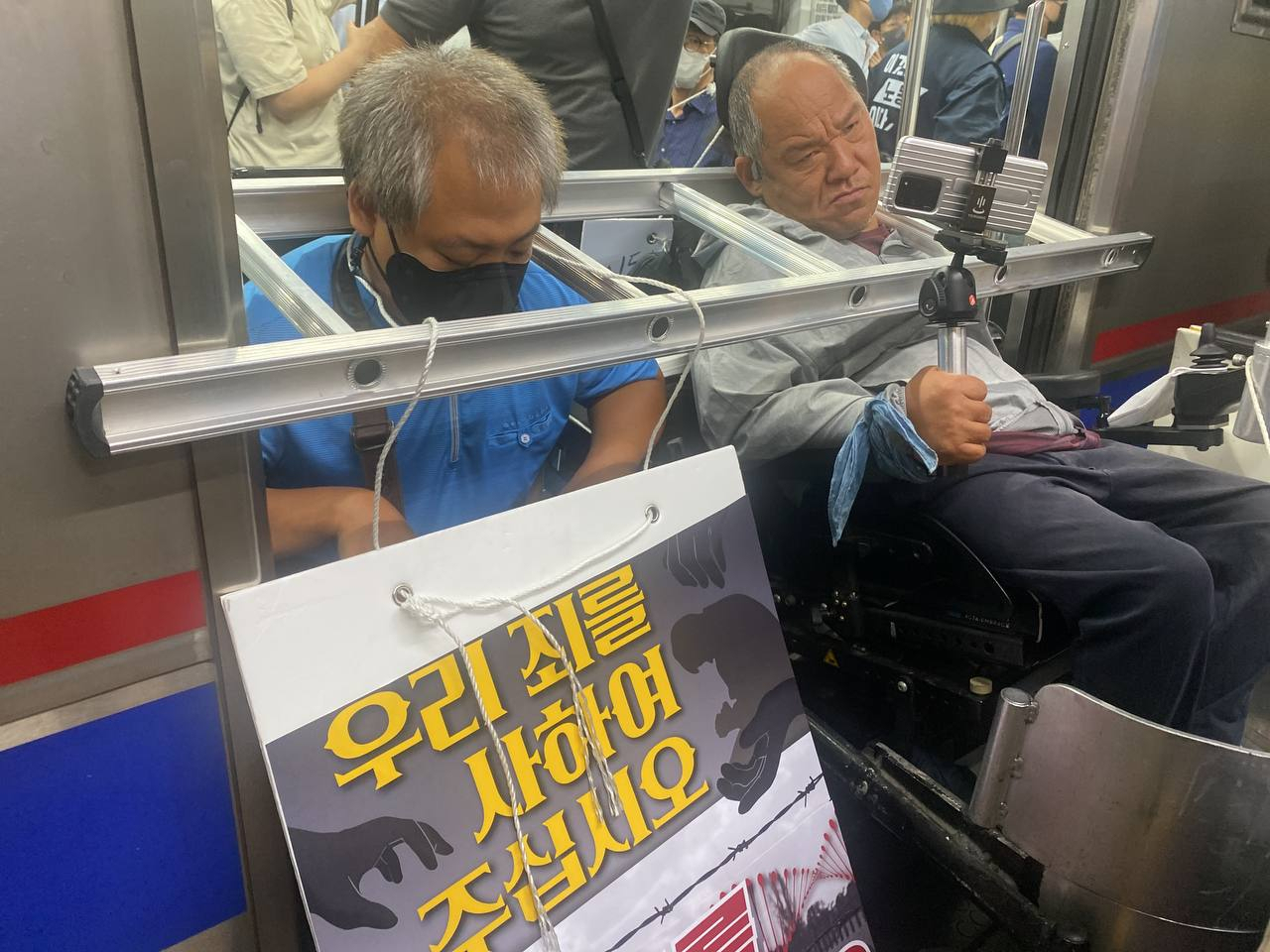 20일 오전 전국장애인차별철폐연대 관계자들이 지하철 4호선 삼각지역에서 출근길 지하철 시위를 하고 있다. 단체 관계자들이 목에 철제 사다리를 쓴 채 열차문이 닫히지 않도록 해 열차가 지연되기도 했다. [전국장애인차별철폐연대 제공]