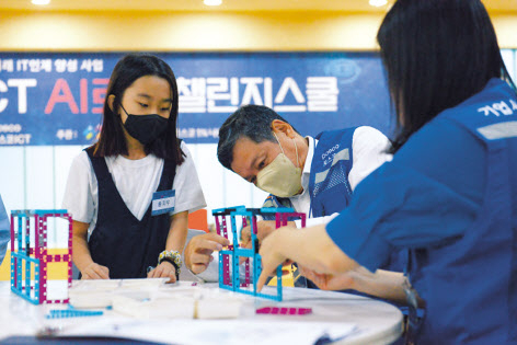 정덕균(가운데) 포스코ICT 사장이 지난 20일 포스코ICT 판교사옥에서 진행된 ‘AI 로봇 챌린지 스쿨’에서 학생들과 함께 AI 로봇을 만들고 있다. [포스코ICT 제공]