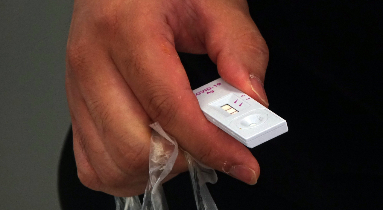 A person holds a COVID-19 kit displaying a positive result at a testing station at Seoul Station in Seoul on June 13, 2022. (Yonhap)