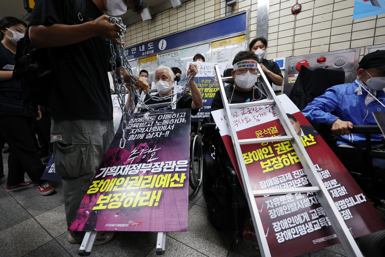 박경석 전국장애인차별철폐연대(전장연) 상임공동대표와 활동가들이 지난 13일 서울 혜화역에서 지하철 집회를 재개하며 장애인권리예산과 이동권 보장을 촉구하고 있다. [연합]