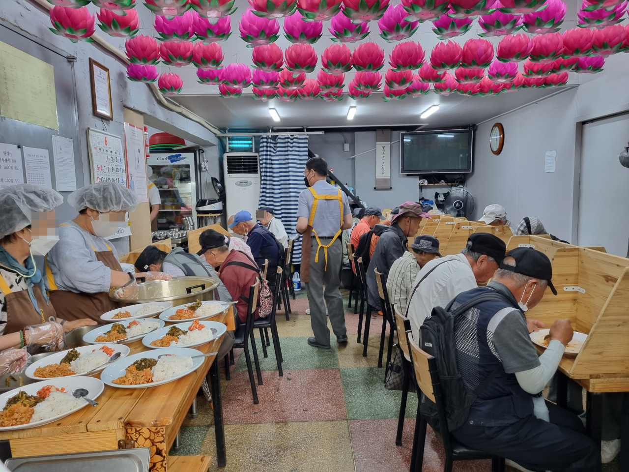지난 24일 서울 종로구 원각사 무료급식소에서 음식을 배급받은 이들이 식사하고 있다. 김영철 기자