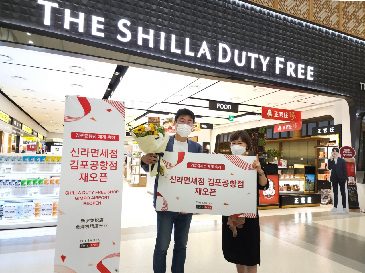 29일 신라면세점 김포국제공항점이 코로나19로 인해 영업을 중단한지 2년 3개월 만에 재오픈했다. 장애리 신라면세점 김포공항점장(사진 오른쪽)이 재오픈 첫 구매 고객에게 꽃다발과 함께기념품을 선물로 증정하고 기념촬영을 하고 있다.[신라면세점 제공]