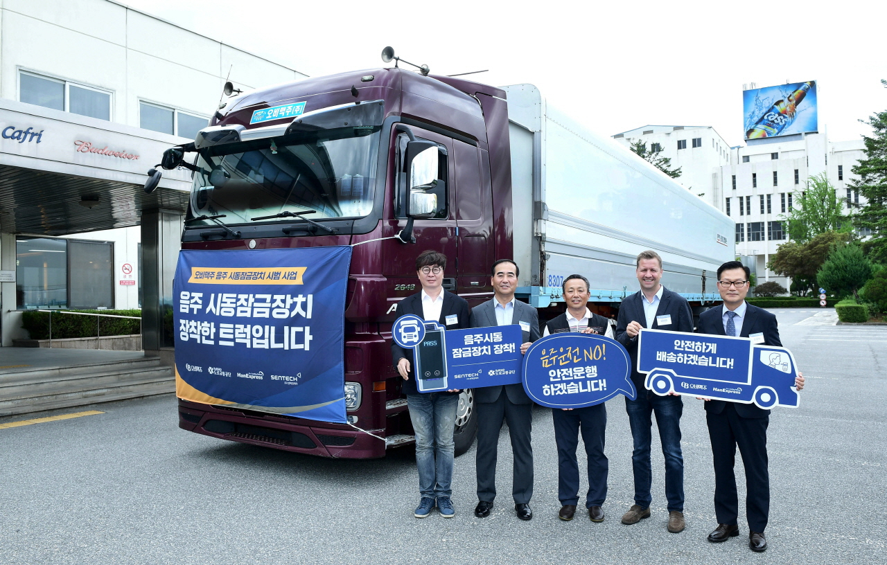 28일 오비맥주 이천공장에서 음주운전방지장치 시범사업을 시작하며 음주운전방지장치를 설치한 트럭 앞에서 센텍코리아 유도준 대표(왼쪽부터), 도로교통공단 이주민 이사장, 화물차주 오비맥주 박영길 지부장, 오비맥주 배하준 대표, 한익스프레스 윤영채 상무가 기념사진을 찍고 있다. [ 오비맥주 제공]