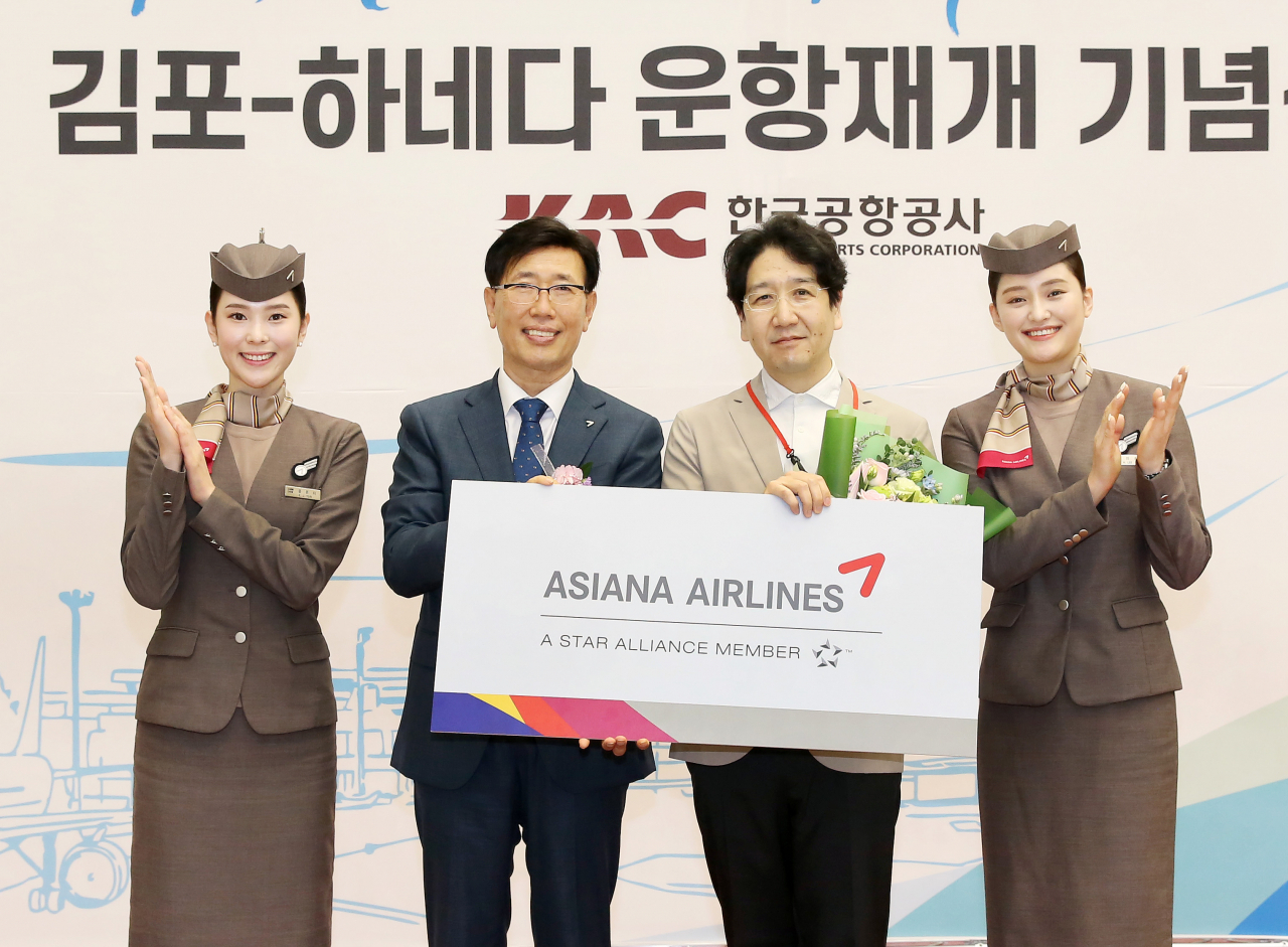 정성권(왼쪽 두 번째) 아시아나항공 대표가 출발편 탑승객 1명에게 김포-하네다 노선 왕복 항공권을 증정한 후 기념촬영을 하고 있다. [아시아나항공 제공]