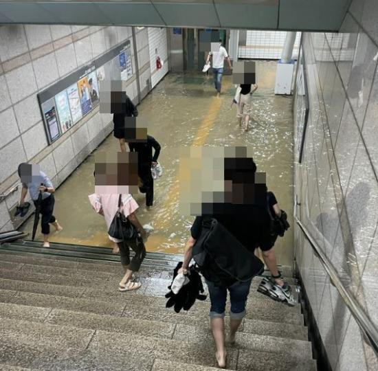 30일 폭우로 인해 침수된 지하철 1호선 세류역 모습. 이용객들이 신발과 양말을 벗은 채 맨발로 길을 건너고 있다. [트위터]