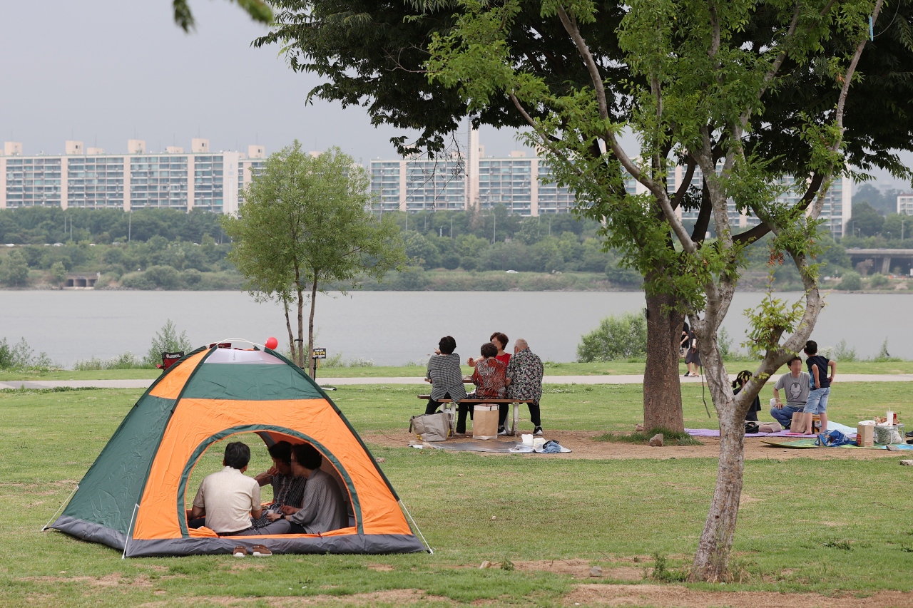 지난달 26일 오후 서울 서초구 반포 한강공원에서 시민들이 텐트 안과 나무 그늘 밑에서 더위를 피하며 쉬고 있다. [연합]