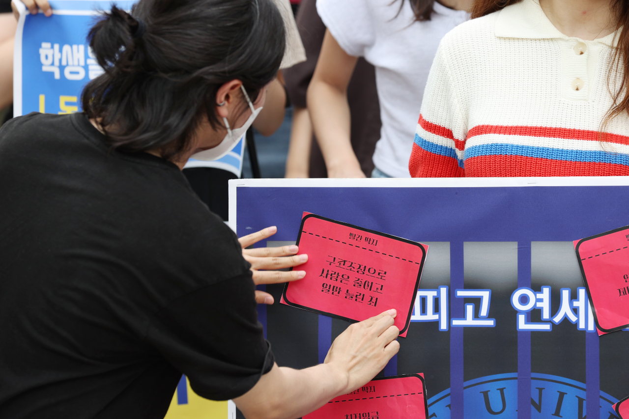지난 6일 오전 서울 서대문구 연세대 백양관 앞에서 열린 ‘청소경비 노동자 투쟁에 연대하는 연대생’ 기자회견에서 한 참가자가 연세대의 잘못이 적힌 빨간 딱지를 부착하는 퍼포먼스를 하고 있다. [연합]