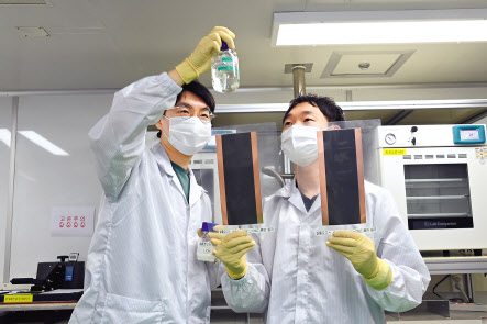ETRI 연구진이 전도성 셀룰로오스 바인더 소재와 전고체 이차전지 음극판을 살펴보고 있다. [ETRI 제공]