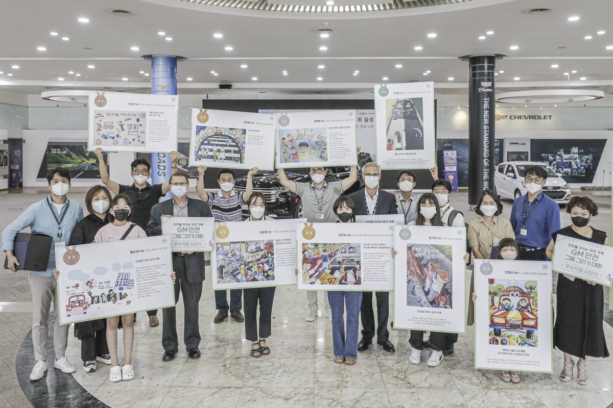 12일 열린 그림 그리기 대회 시상식에 참여한 GM 한국사업장 리더십 및 직원 가족들이 그림을 들고 있다. [한국지엠 제공]