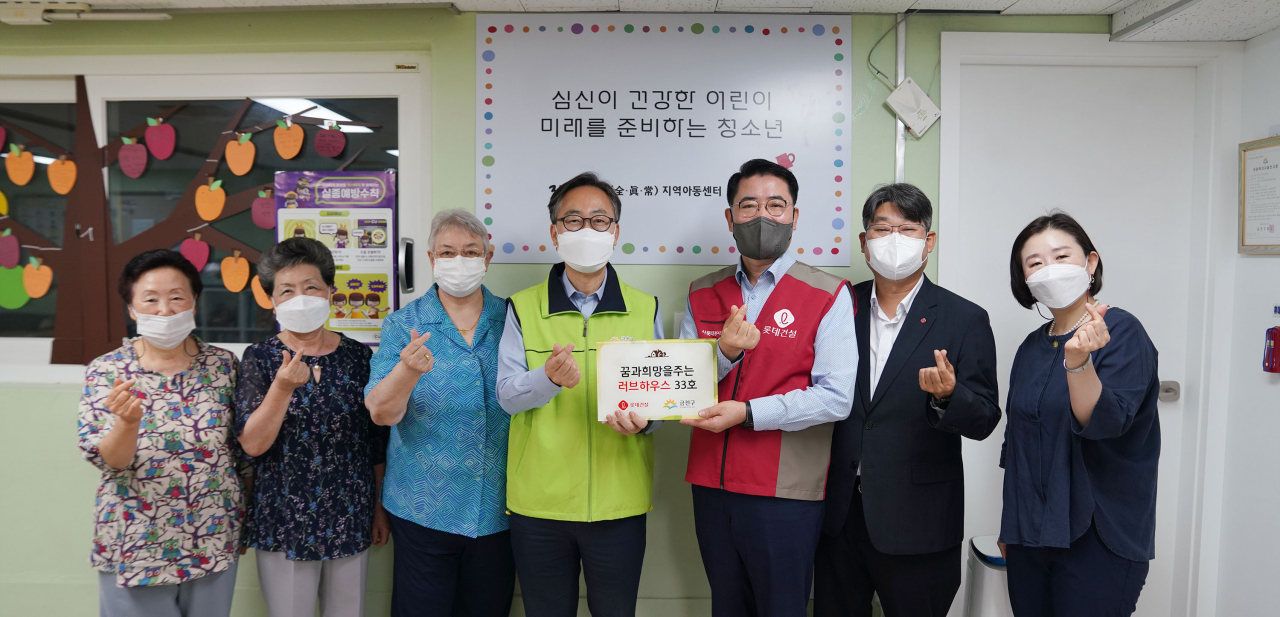 롯데건설 주택사업본부 이부용 본부장(오른쪽에서 세 번째), 유성훈 금천구청장(오른쪽 네 번째)과 관계자들이 함께 기증판을 전달하고 있다.