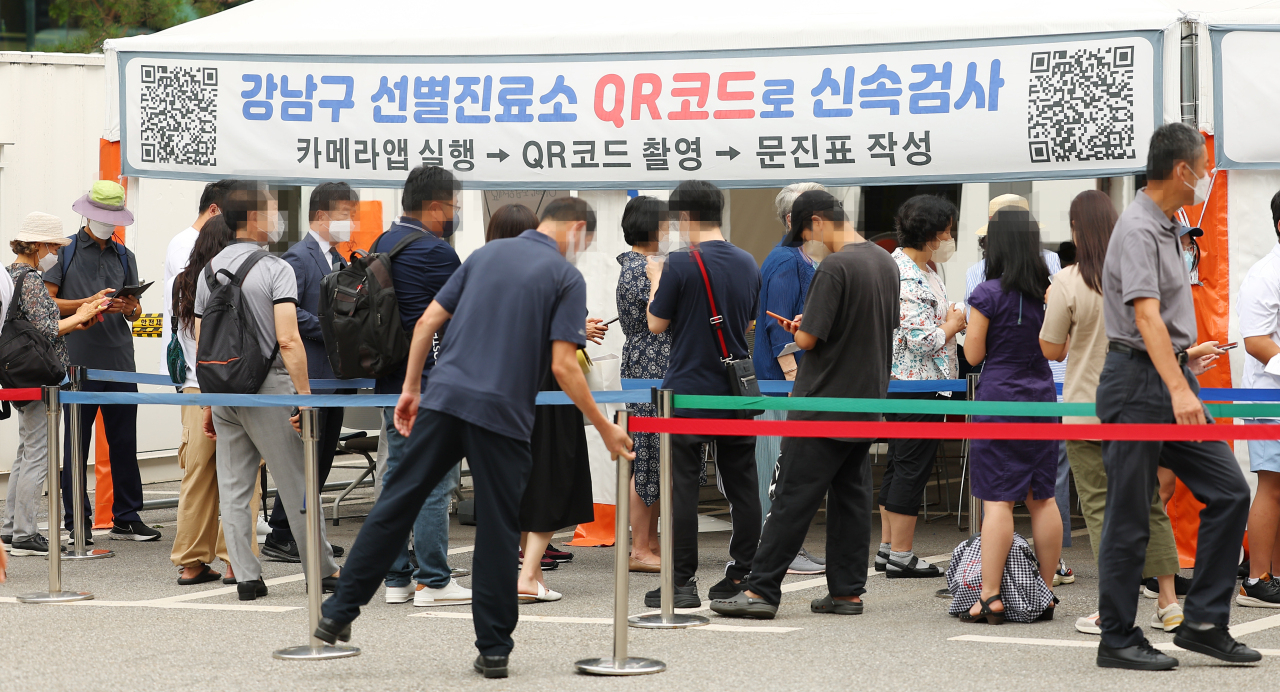 People wait in line at a local COVID-19 testing station in Gangnam-gu, Seoul, Tuesday. (Yonhap)