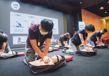 SK-T타워내 수펙스홀에서 강종렬 SKT CSPO(안전보건 최고경영책임자, 앞줄 왼쪽 첫번째)와 전환희 노조위원장(앞줄 왼쪽에서 두번째)을 비롯한 구성원들이 심폐소생술 실습 교육을 받는 모습. [SK텔레콤 제공]