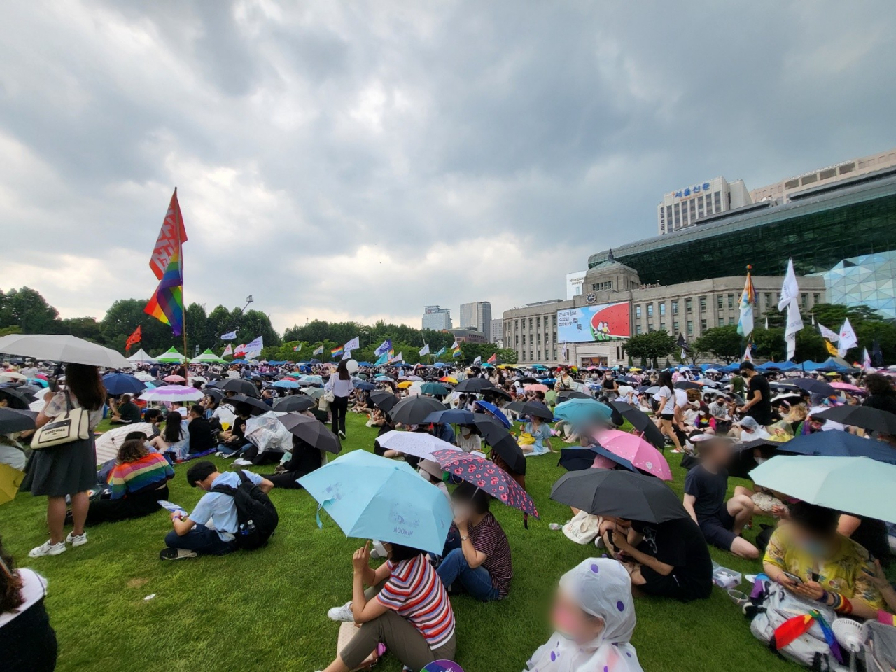 16일 서울 중구 서울광장에서 열린 서울퀴어문화축제 도중 소나기가 내리자, 참가자들이 우산을 쓰고 행사를 지켜보고 있다. 박혜원 기자