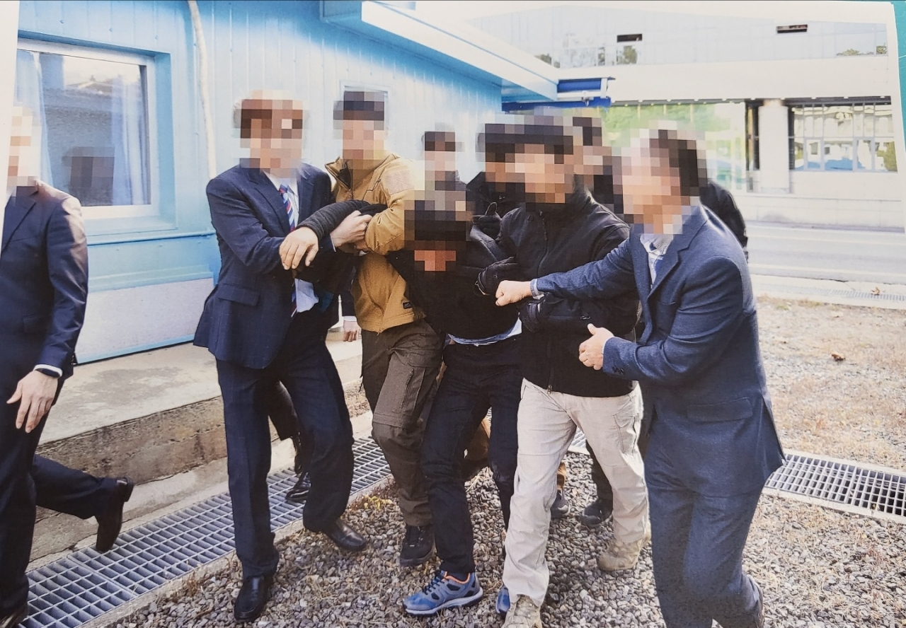 In this photograph released by the Ministry of Unification, North Korean fishermen are apparently dragged by officials to be handed over to North Korea via the Military Demarcation Line.