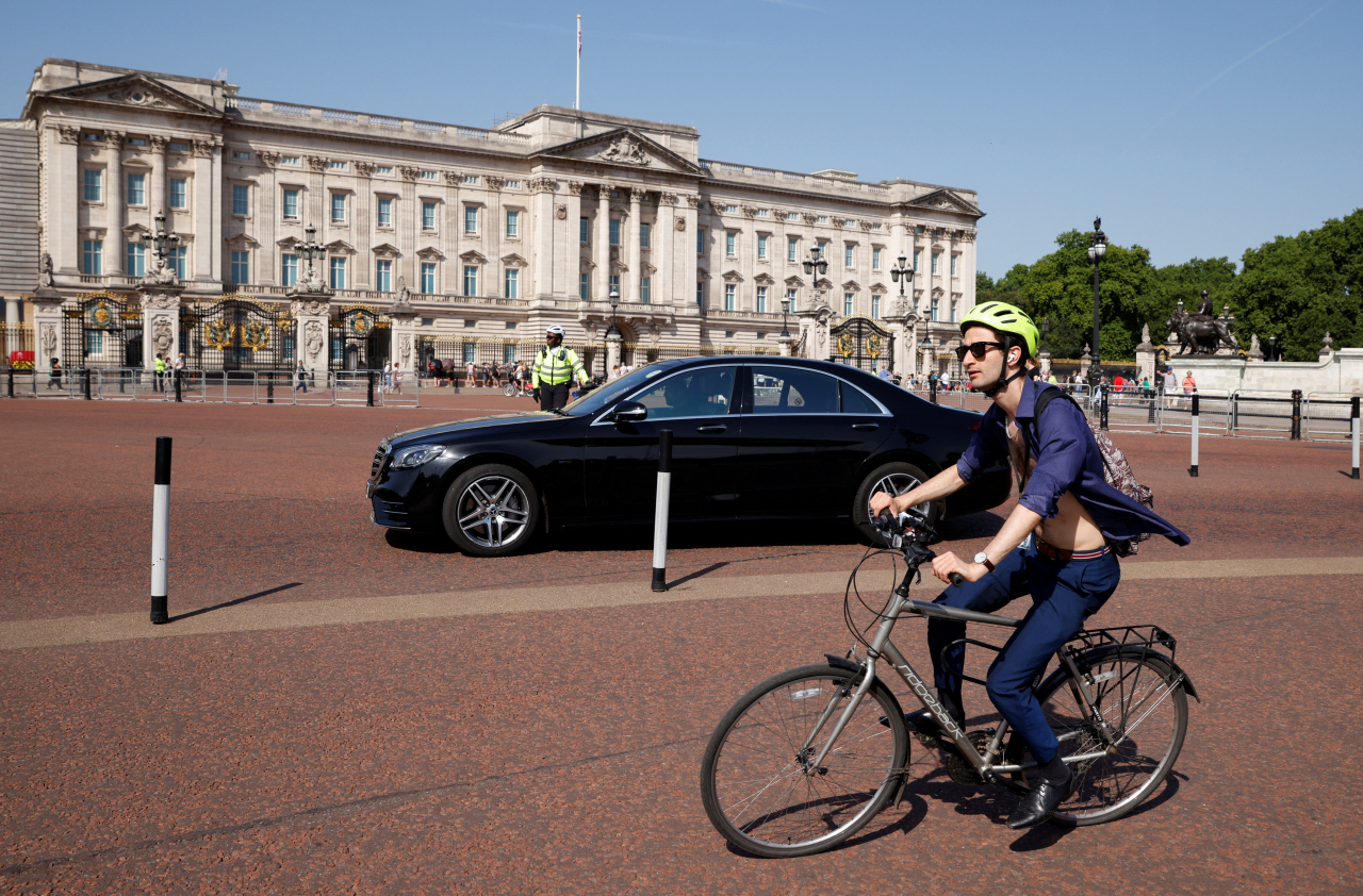 신사의 나라 영국도 더위 앞에서 체면을 내려놨다. 18일(현지시간) 영국 버킹검 궁 앞에서 한 남성이 셔츠 앞 단추를 모두 풀어헤쳐 상반신을 드러낸 채 자전거를 이용해 도로를 지나가고 있다. [로이터]