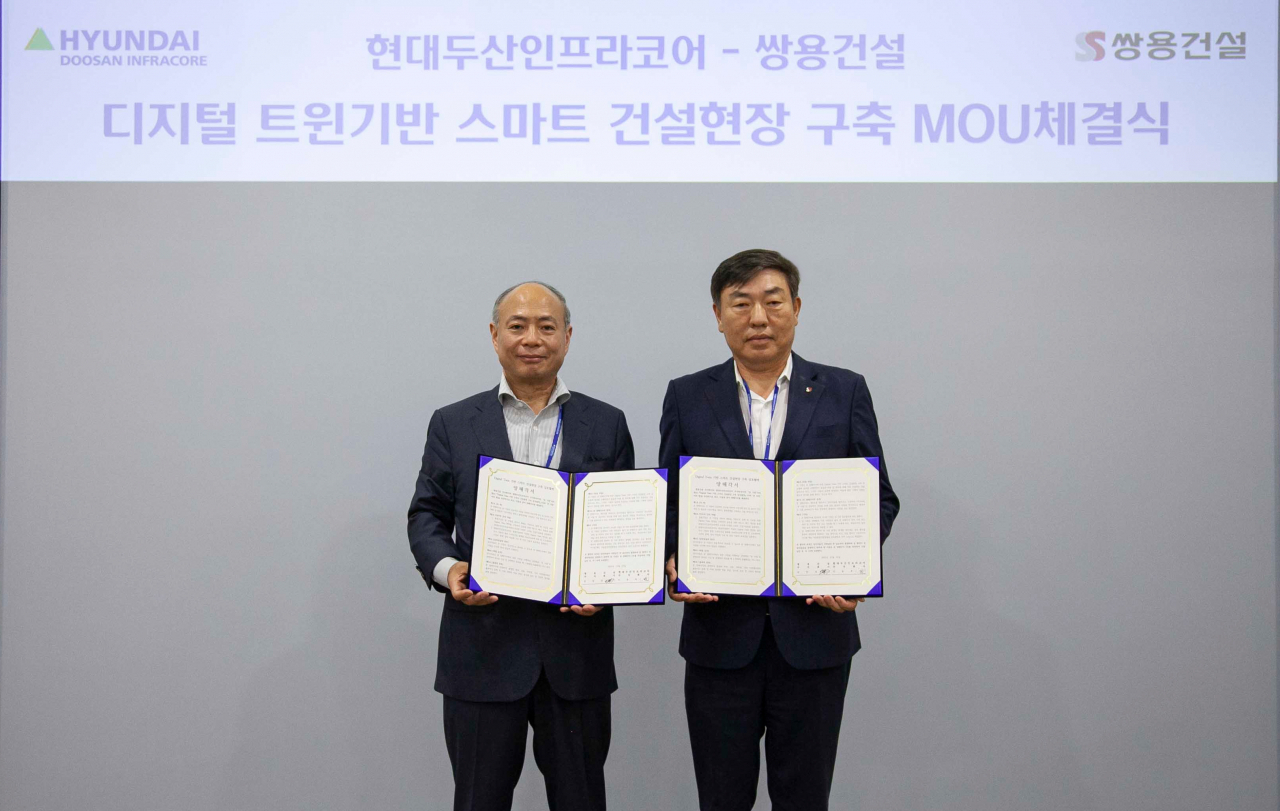 이동욱(왼쪽) 현대두산인프라코어 기술원 부사장과 김민경 쌍용건설 토목본부장이 기념촬영을 하고 있다. [현대두산인프라코어 제공]