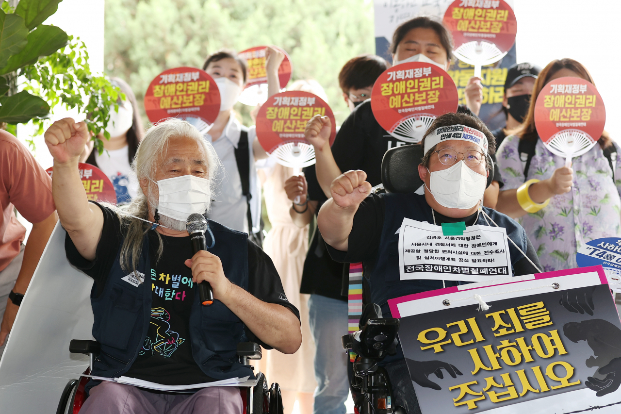 전국장애인차별철폐연대(전장연) 활동가들이 19일 오전 서울 용산경찰서에서 열린 전장연 경찰 조사 자진출석·김광호 서울경찰청장 법 준수 촉구 기자회견에서 구호를 외치고 있다. 박경석(왼쪽) 전장연 상임공동대표는 이날 "용산서에 엘리베이터가 없다"며 경찰 조사를 거부하고 입장문을 전달했다. [연합]