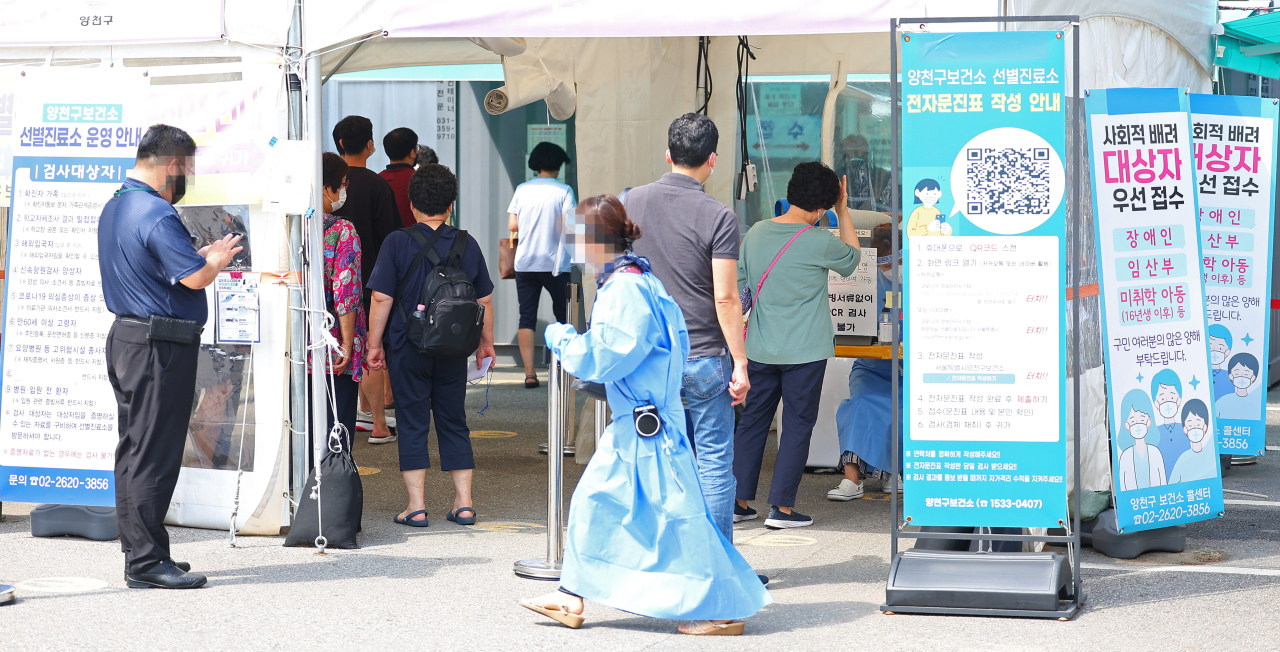 People wait in line at a local COVID-19 testing station, Monday. (Yonhap)