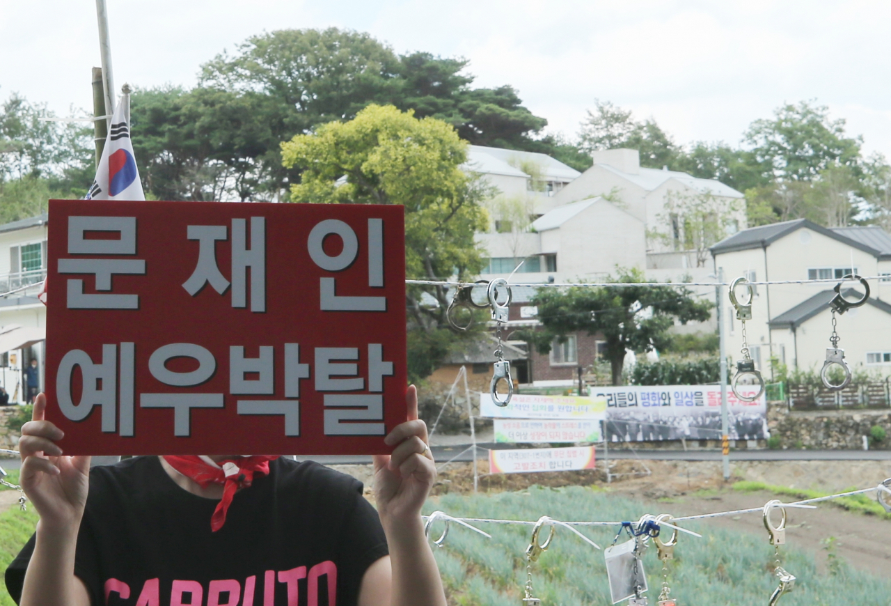 문재인 전 대통령에 반대하는 한 단체의 회원이 지난 17일 오후 경남 양산시 하북면 지산리 평산마을 문 전 대통령 사저 앞에서 전직 대통령 예우를 박탈하라는 피켓을 들고 시위를 하고 있다. [연합]