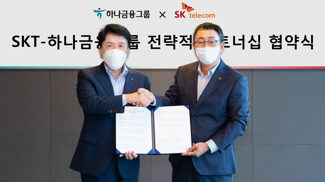 Hana Financial Group Chairman Ham Young-joo, left, and SK Telecom CEO Ryu Young-sang shake hands at an event celebrating their new ESG and ICT partnership at the telecom giant's headquarters in central Seoul on Friday. (Hana Financial Group)