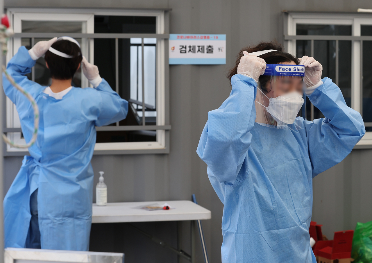 코로나19 재확산으로 25일 오후 다시 문을 연 서울 중구 서울역 임시선별검사소에서 의료진이 검사를 준비하며 페이스실드를 착용하고 있다. [연합]