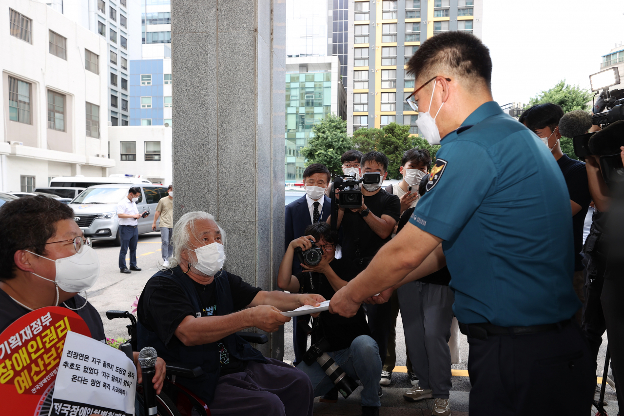 박경석 전국장애인차별철폐연대(전장연) 상임대표가 14일 오후 서울 종로구 혜화경찰서에서 양일홍 혜화서 경무과장에게 입장문을 전달하고 있다. 박 상임대표는 이날 혜화경찰서에 엘리베이터가 설치되면 경찰 조사에 임하겠다고 밝혔다. [연합]